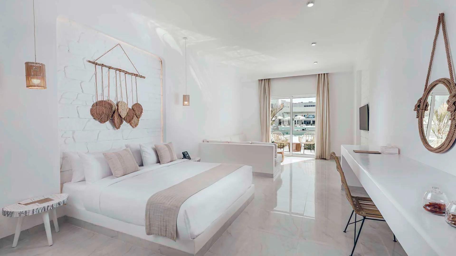 A Large White Room With A Bed And A Table