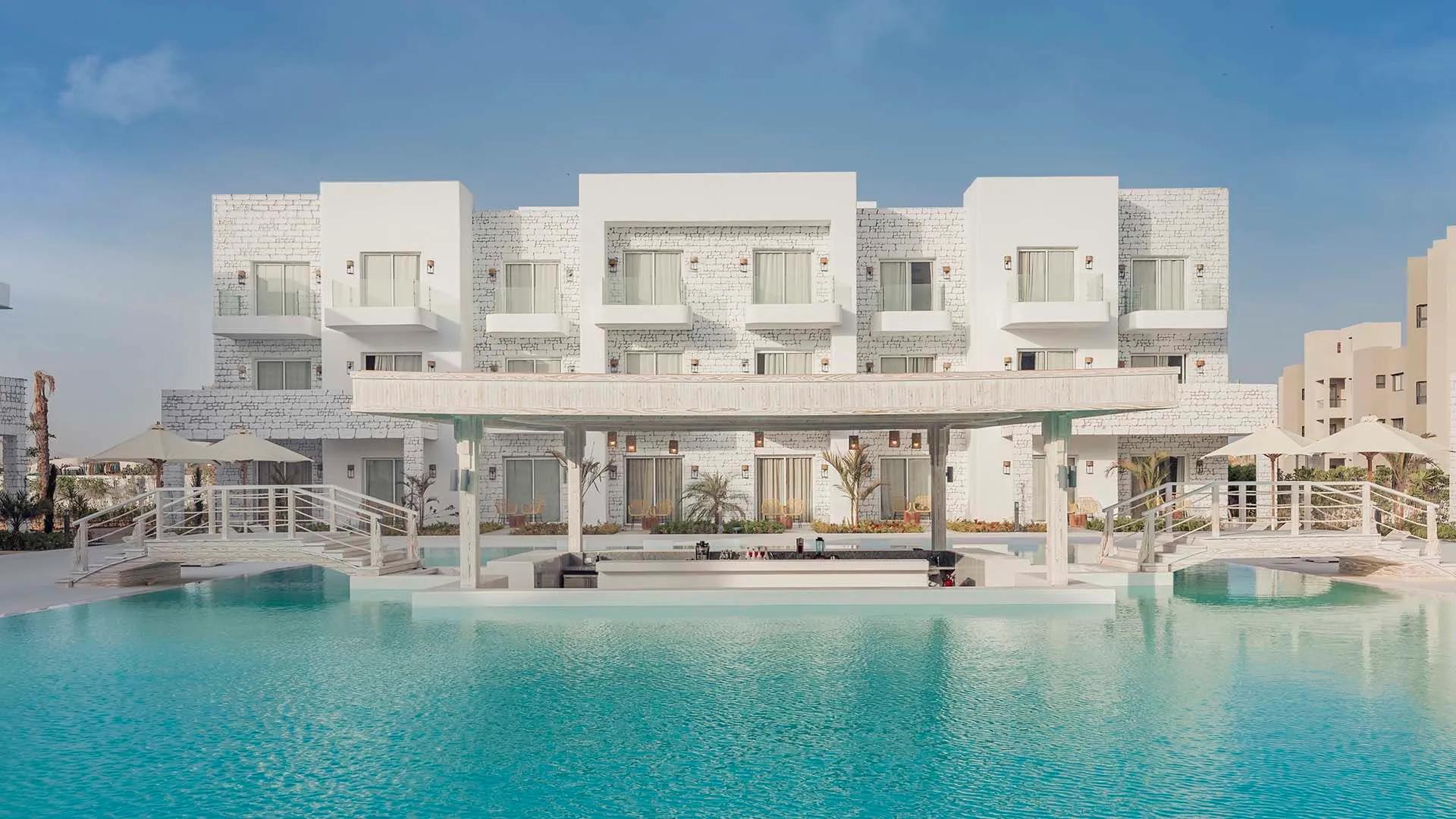 A Large White Building Next To A Pool