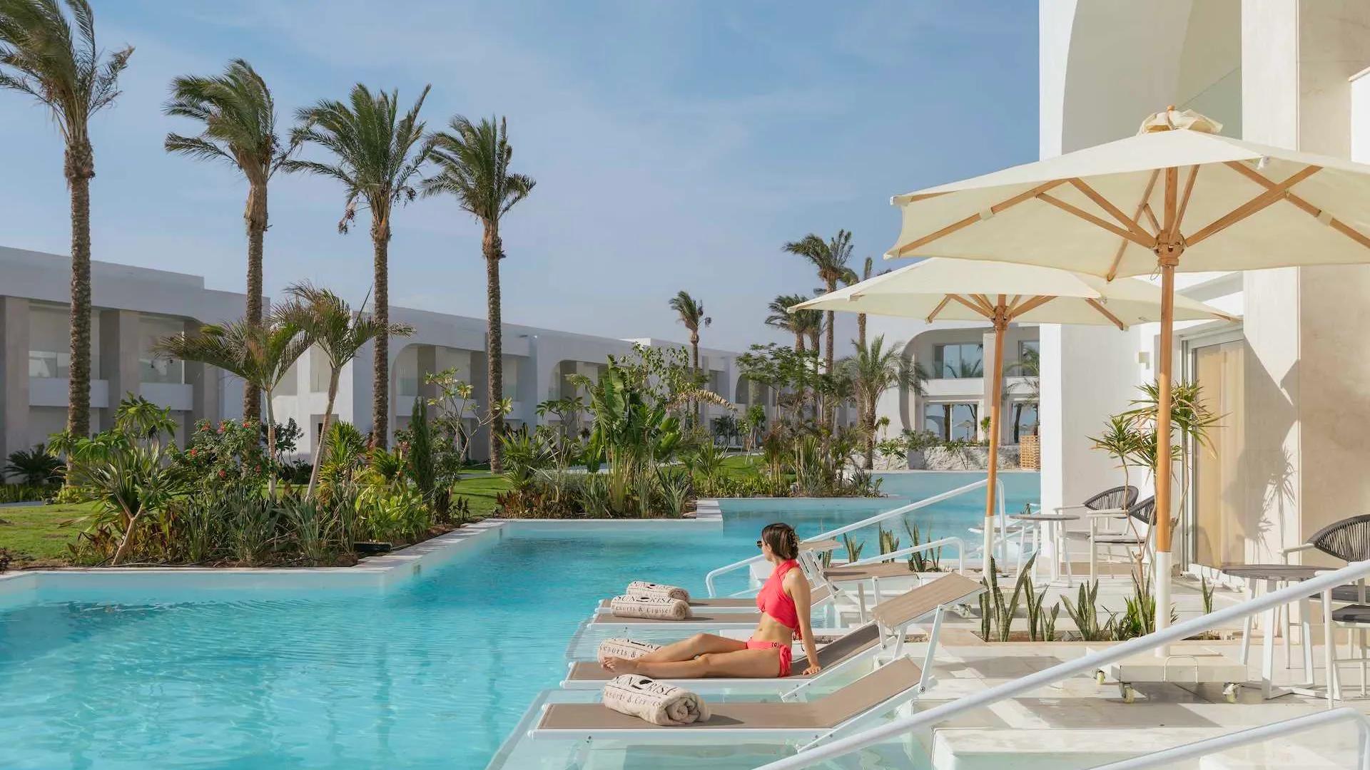 A Person Sitting On A Lounge Chair By A Pool
