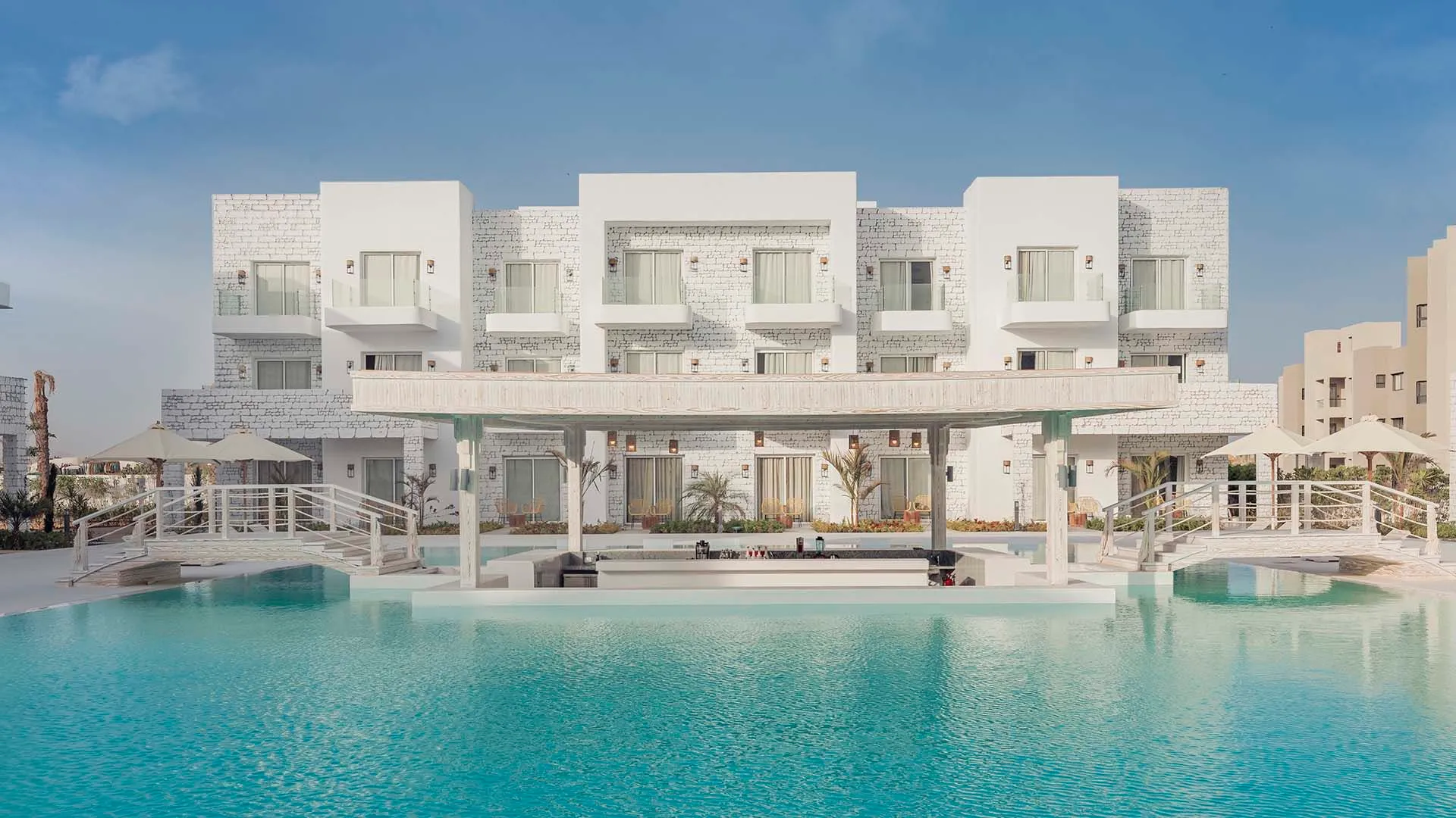 A Large White Building Next To A Pool